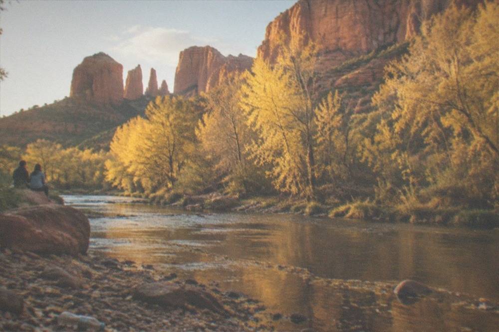 Golden autumn trees along a creek at the base of red rock cliffs near Sedona