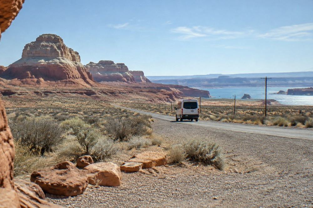 Open high-desert highway stretching toward distant mesas under a wide sky