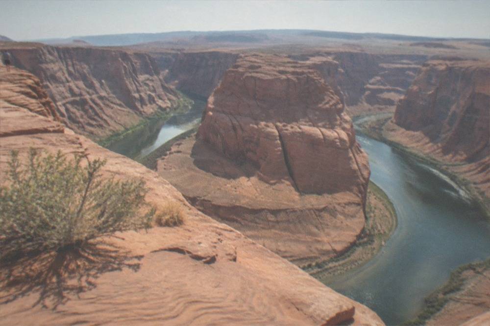 A wide river bend curving around a tall red sandstone cliff under an open sky
