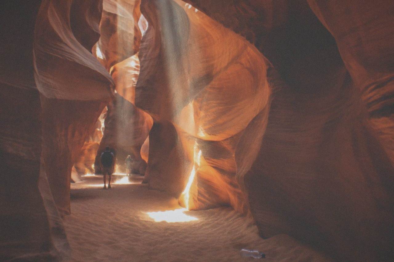 Sunlight beams falling into a narrow winding sandstone slot canyon