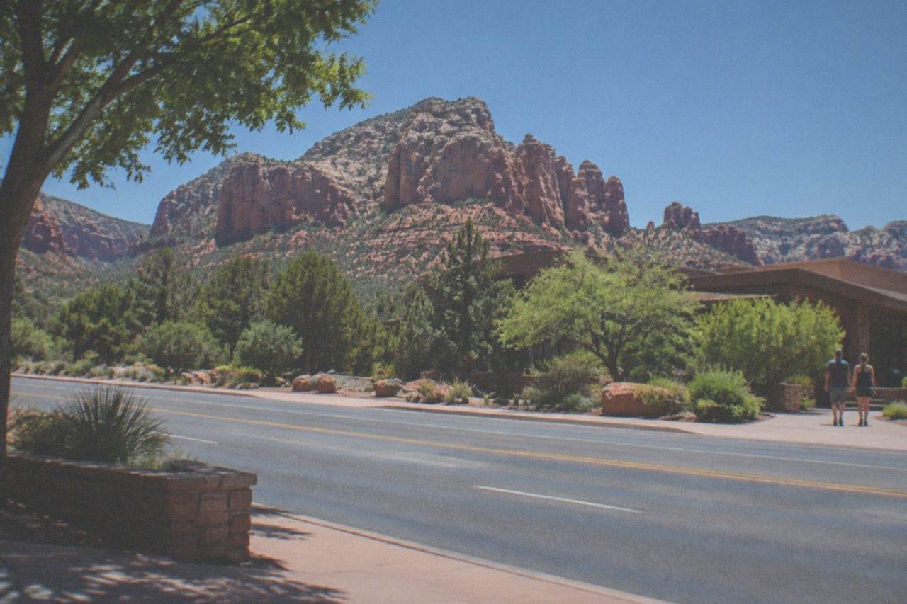 Red rock cliffs rising above pine trees near Sedona under a wide blue sky