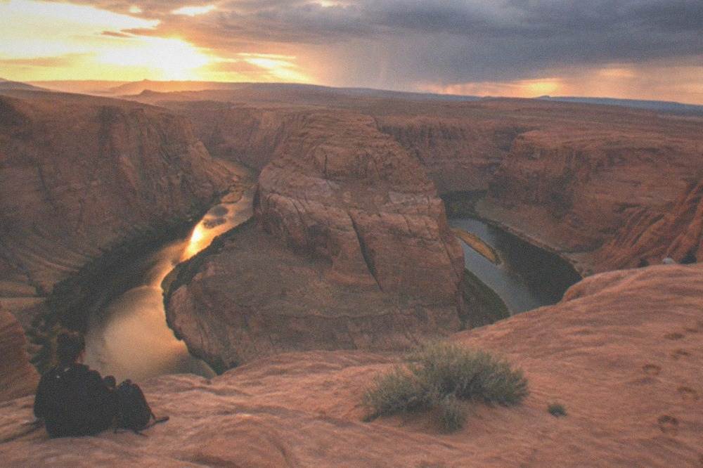 A wide desert overlook above a deep river gorge at golden hour