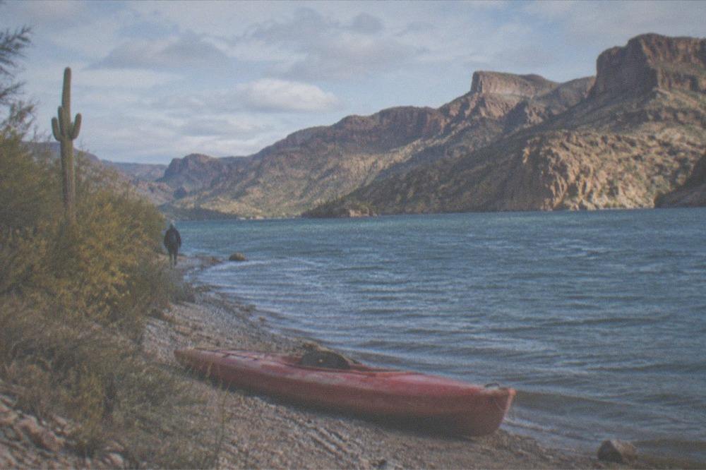 Layered red rock cliffs above a blue desert lake shoreline