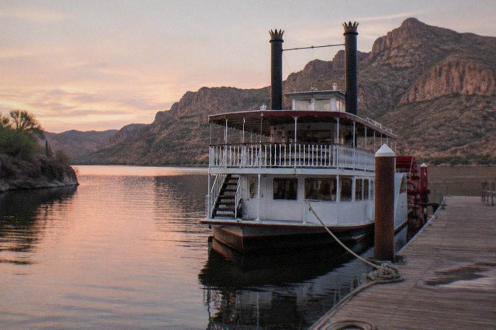 A paddle steamer moored on a small desert lake between rocky hills