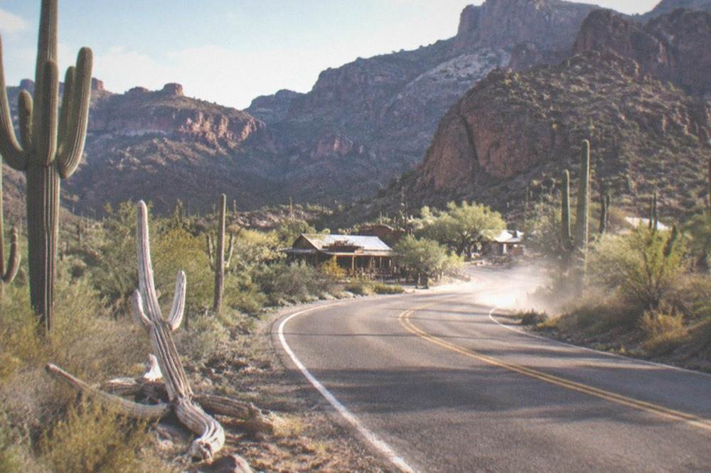 Desert highway curving past saguaro cactus toward canyon country