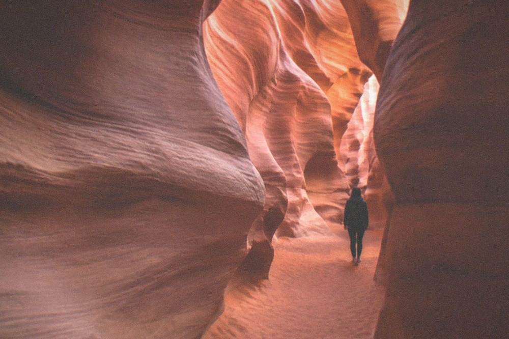 Curved sandstone walls glowing with soft reflected light in a quiet slot canyon