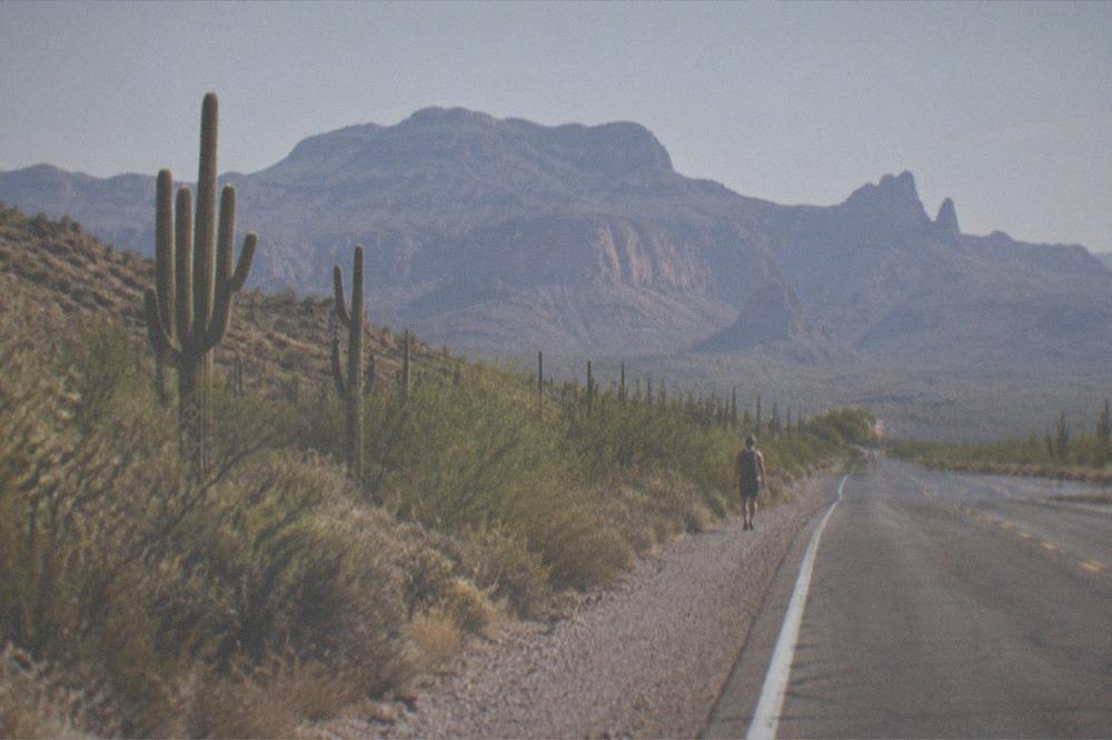 A desert highway heading toward red rock mesas under a wide sky