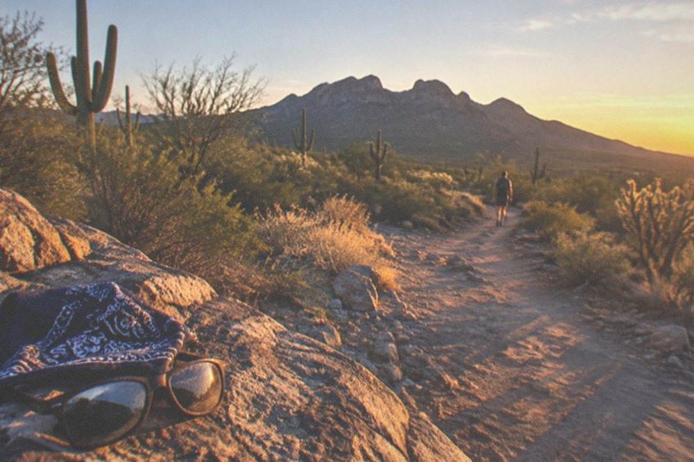 Golden evening light on desert hills with long shadows across the trail