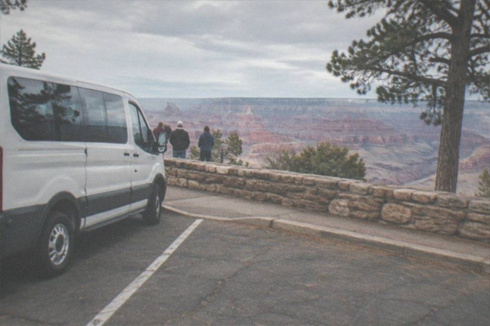 Tour van parked at a Grand Canyon overlook in late afternoon light
