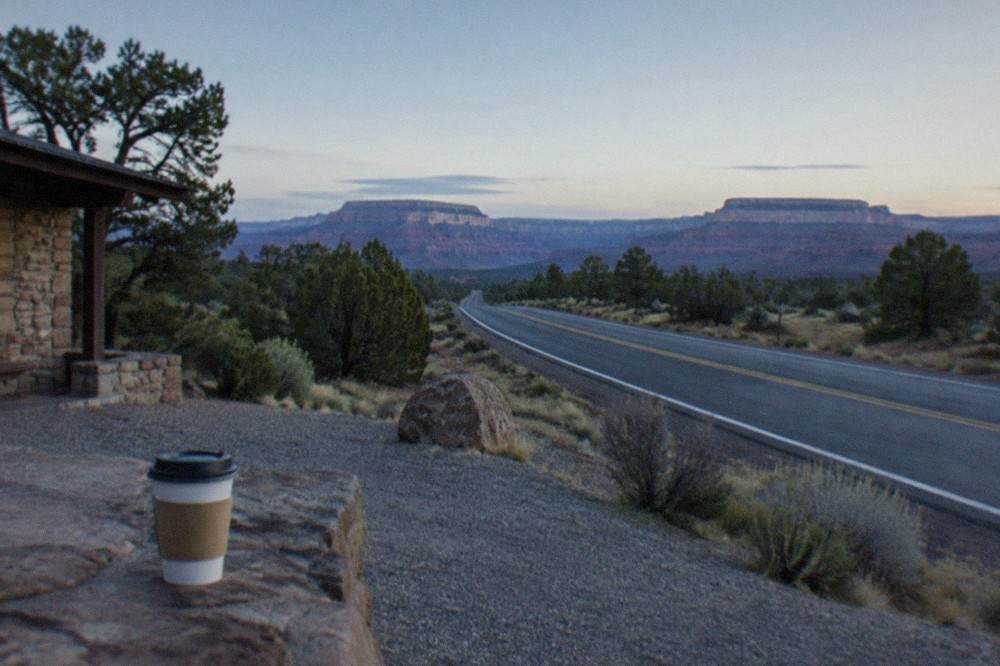 Desert highway heading north through open Arizona scrubland toward distant mesas