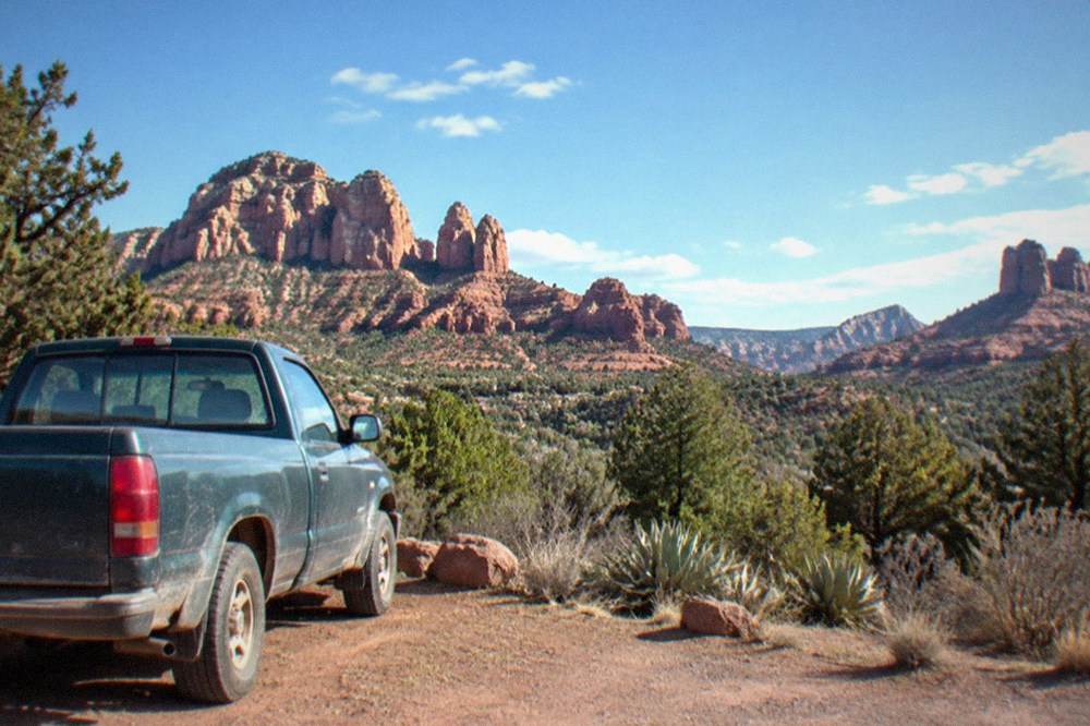 Red rock spires near Sedona under a wide blue sky with juniper scrub in the foreground