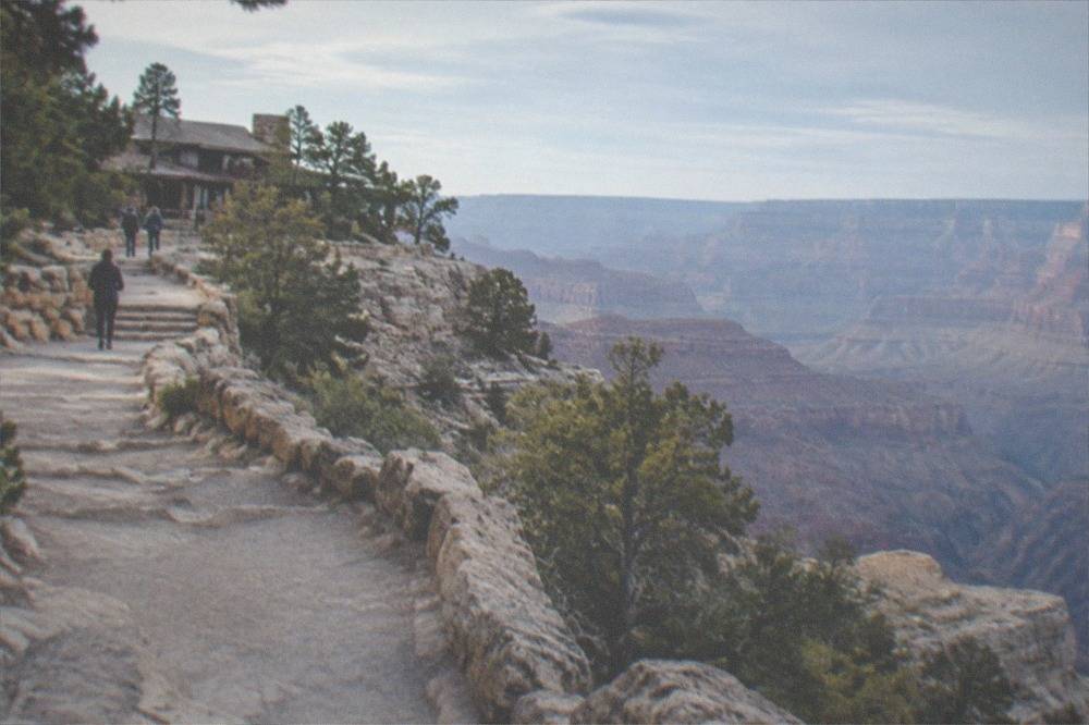 Stone rim trail winding along the canyon edge with layered rock cliffs dropping away below