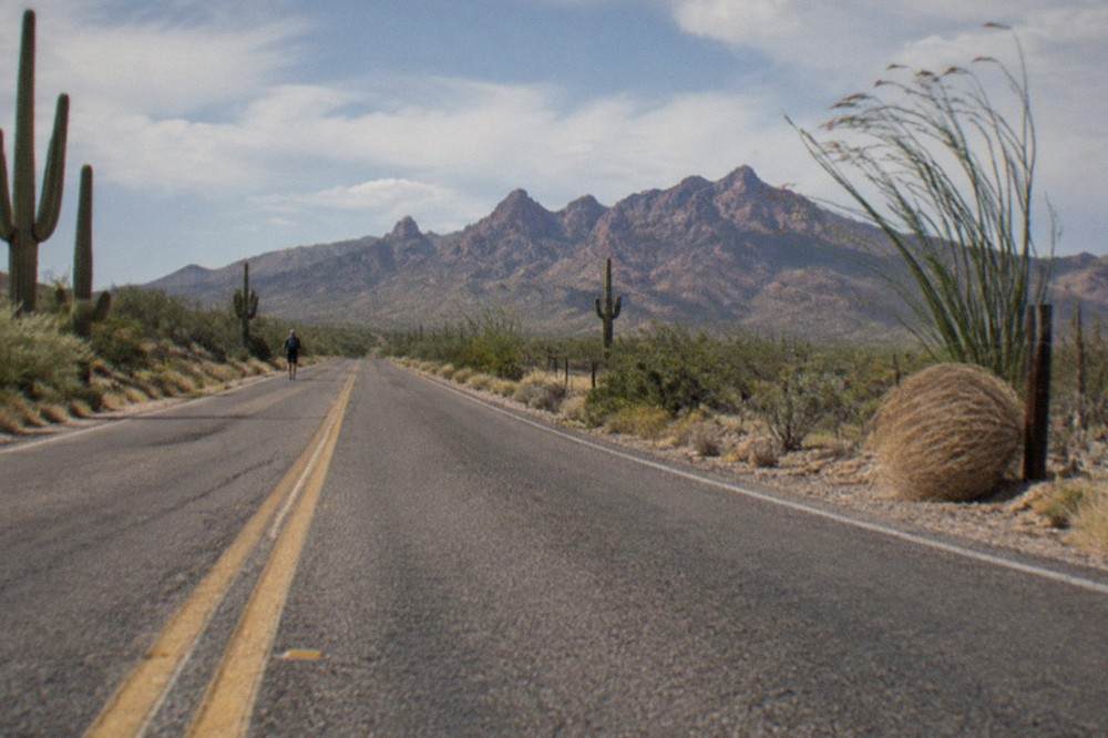 A desert highway stretching toward distant red rock mesas under a clear sky