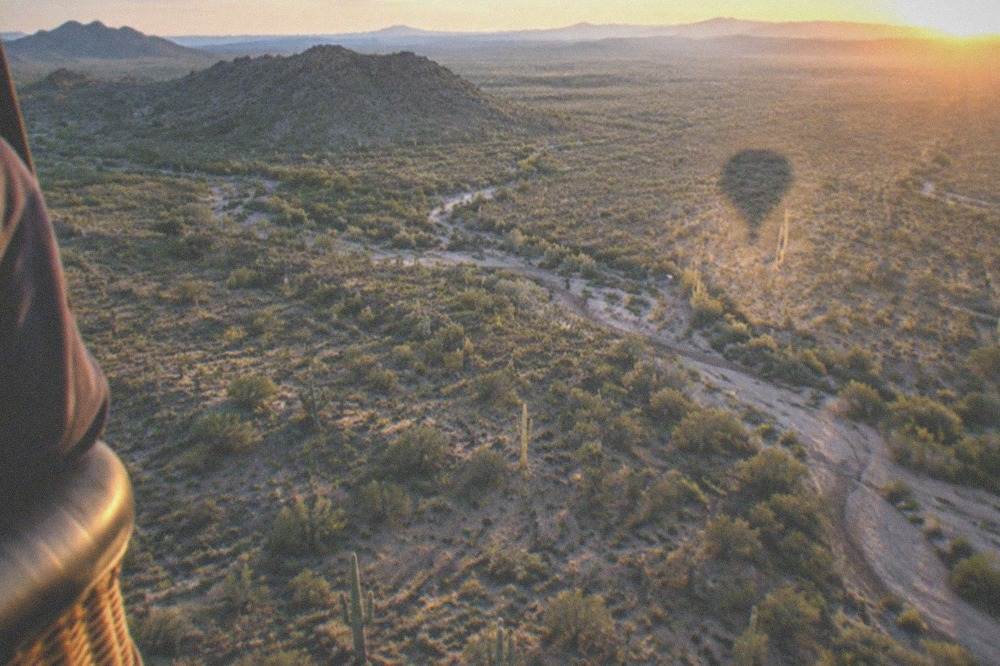 A view from a balloon basket over sprawling Sonoran Desert with long morning shadows across saguaro cactus