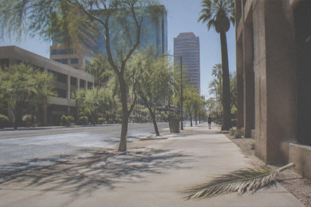 An empty city street under intense midday sun with heat shimmer on the pavement