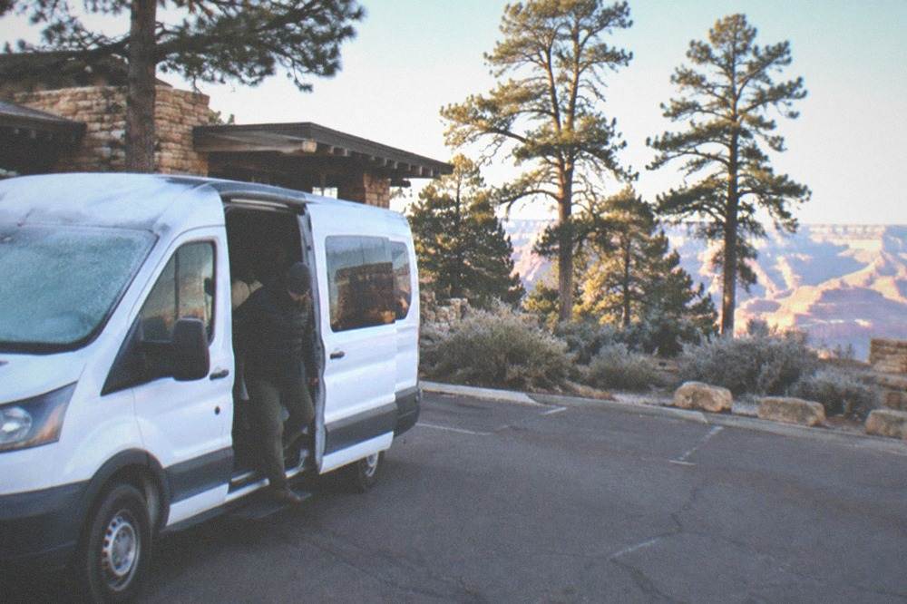 Tour van parked at a Grand Canyon overlook in morning light