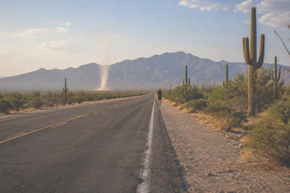 An empty desert highway stretching toward distant mountains in southern Arizona